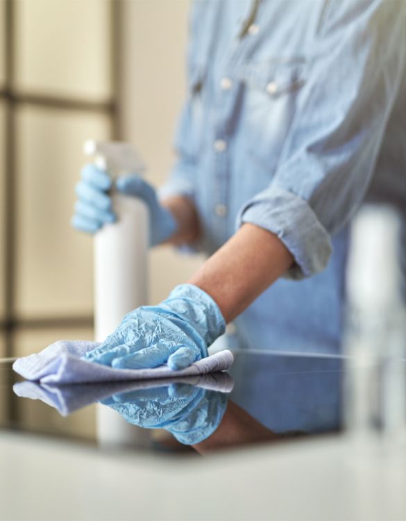 Close up shot of female hands in rubber gloves cleaning cooktop in the kitchen using cloth and spray detergent. Disinfection, cleanliness and housekeeping concept