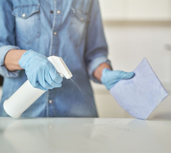 Close up shot of female hands in rubber gloves cleaning cooktop in the kitchen using cloth and spray detergent. Disinfection, cleanliness and housekeeping concept