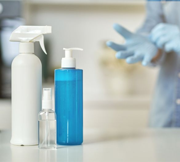 Close up shot of female hands in rubber gloves cleaning cooktop in the kitchen using cloth and spray detergent. Disinfection, cleanliness and housekeeping concept